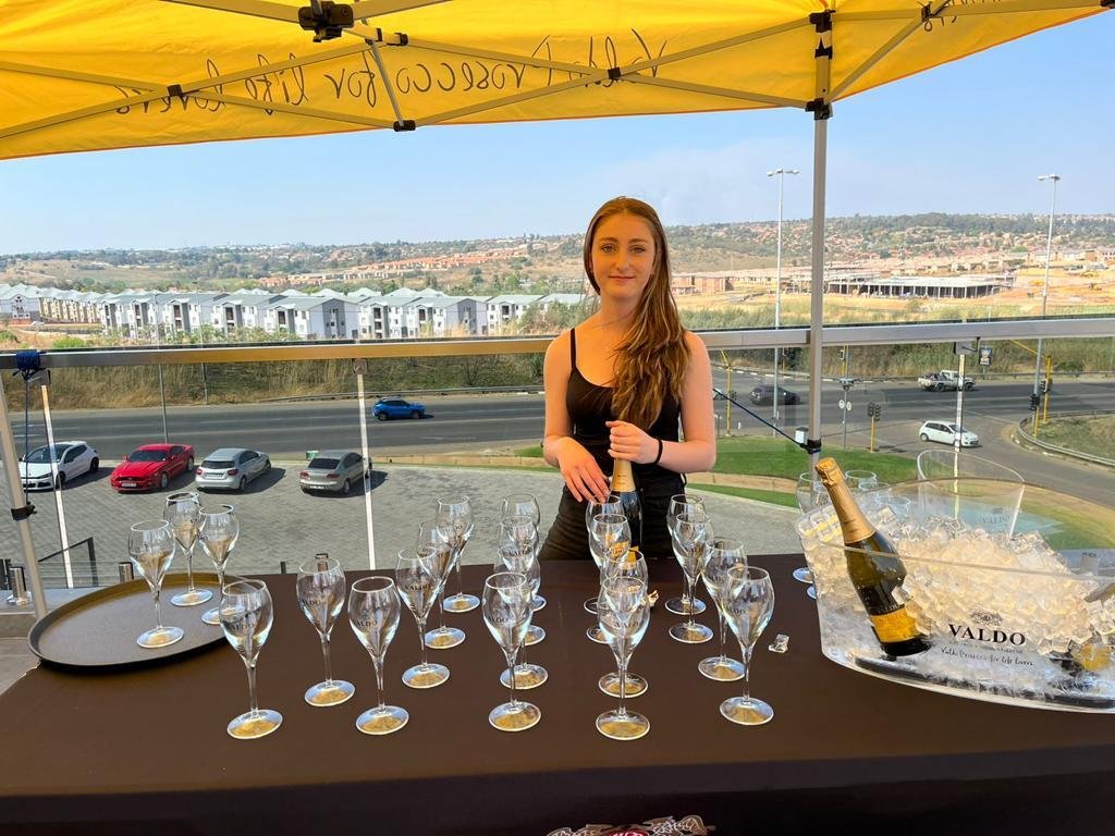 A woman standing in front of a table with champagne glasses at Jr Promotions Western Cape.