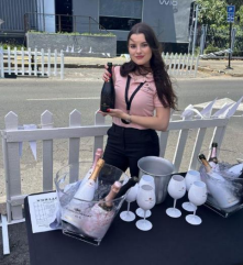 A woman standing in front of a table with bottles of Veuve Du Vernay champagne.